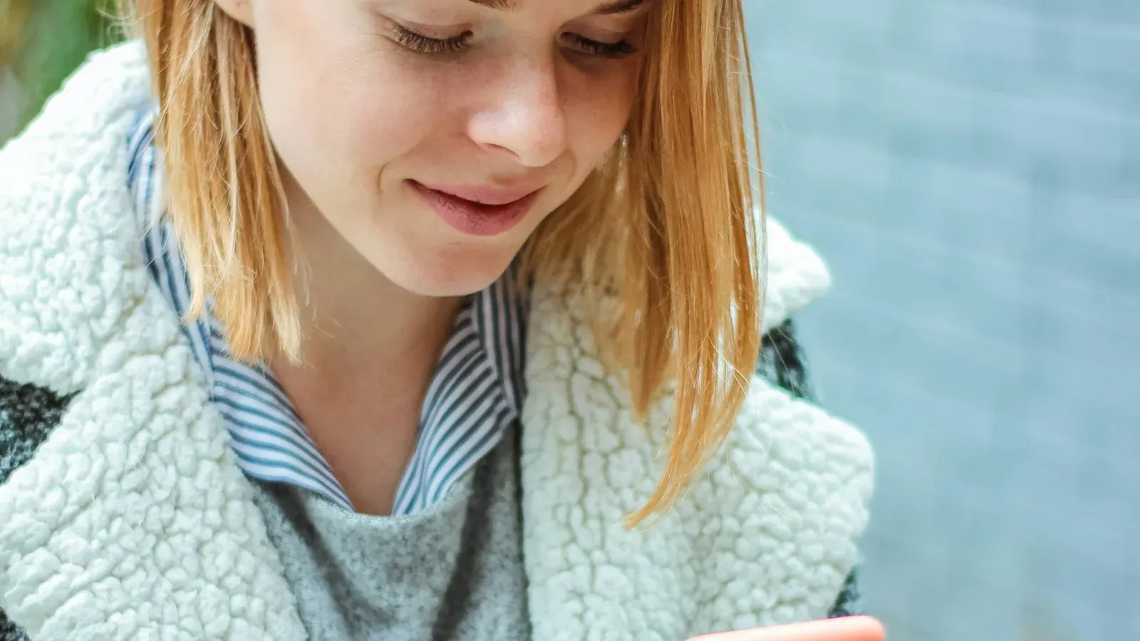Frau lächelt beim Schreiben auf ihr Smartphone – Flirten im Chat