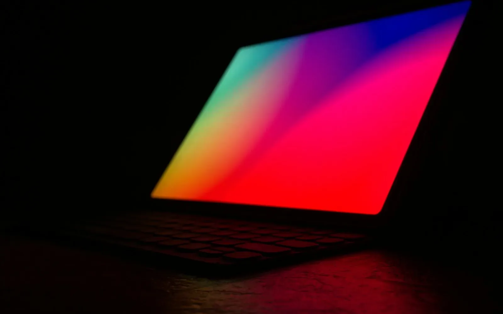 Laptop mit leuchtend buntem Bildschirm im dunklen Raum