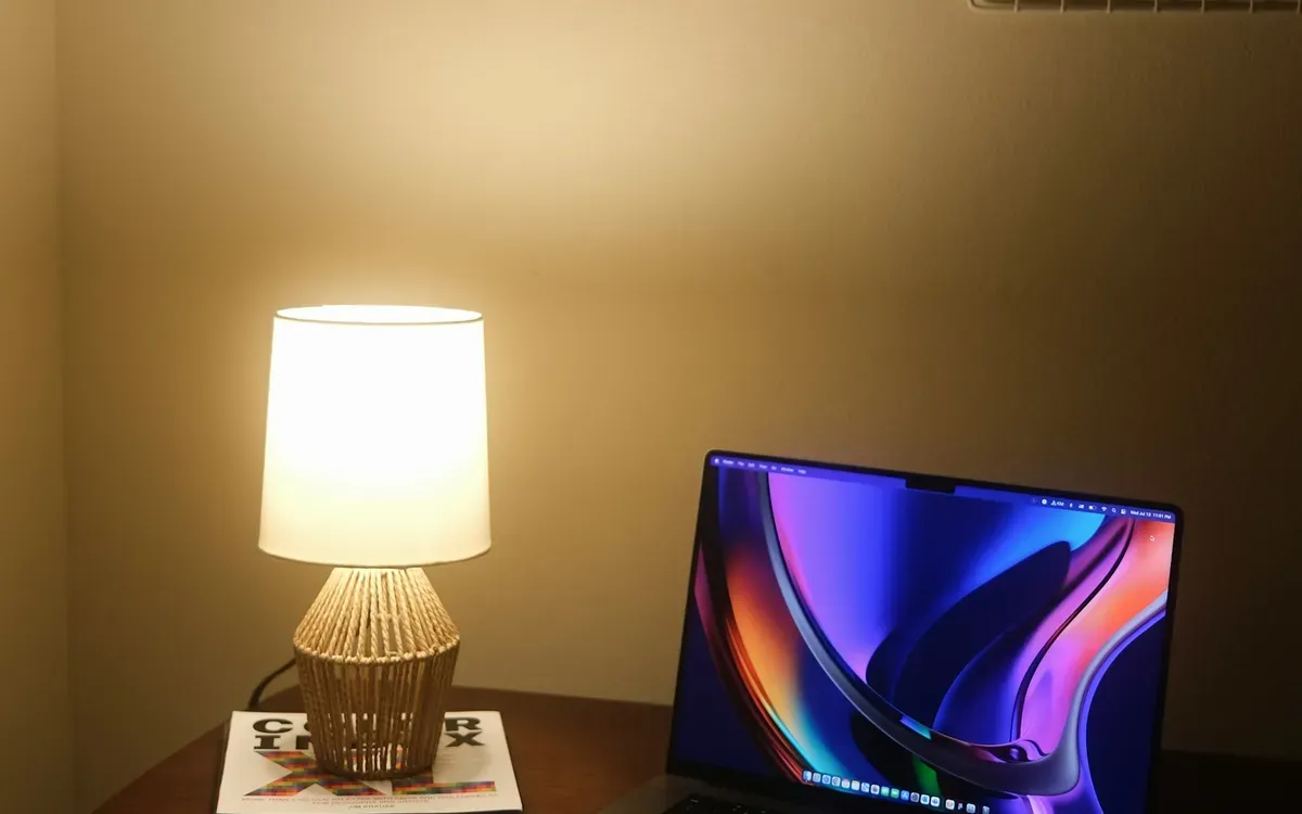 Laptop neben einer warm leuchtenden Tischlampe am Abend