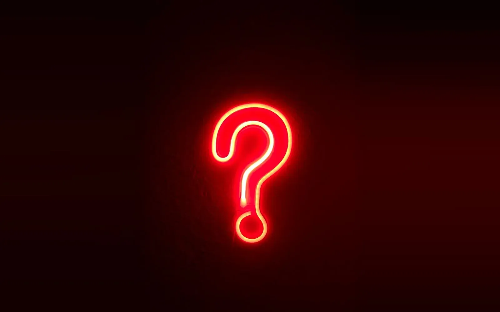 Rot leuchtendes Neon-Fragezeichen an einer dunklen Wand – Flirtfragen im Chat