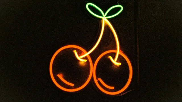 Leuchtende Neon-Kirschen vor dunklem Hintergrund – keine Antwort im Chat
