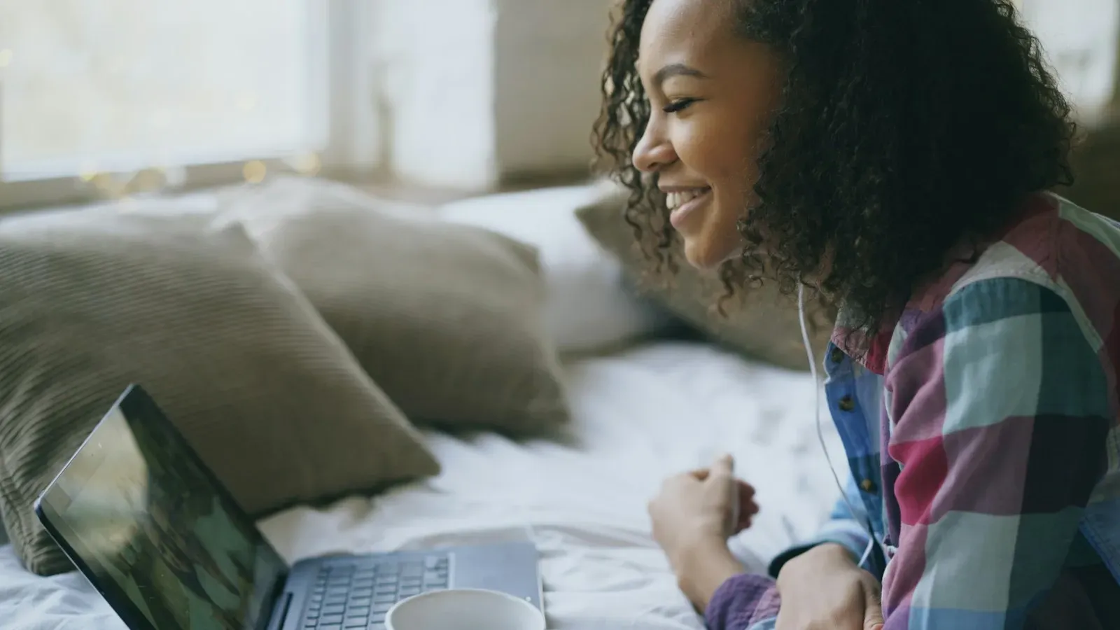 Frau lacht während eines Videochats am Laptop – Flirten im Videochat
